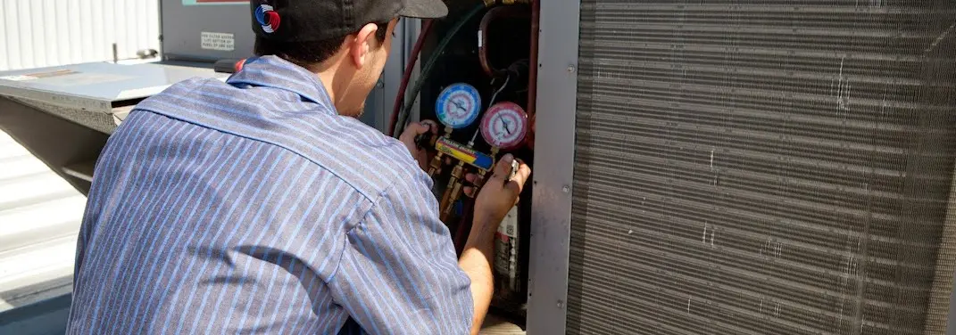 HVAC technician servicing a condenser unit in Decorah